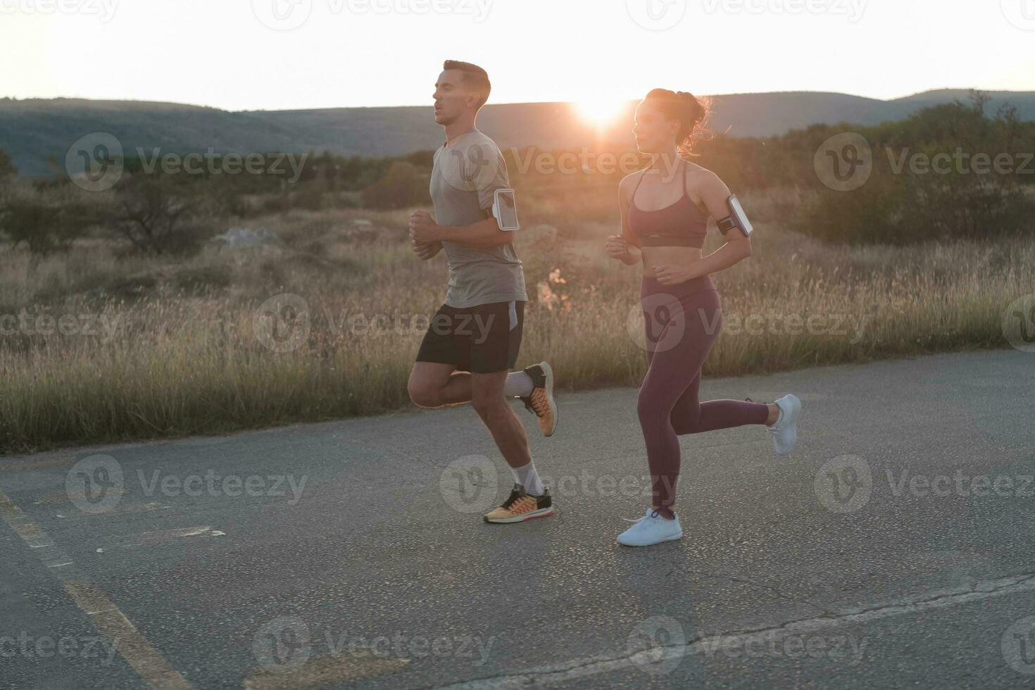 healthy young couple jogging in the city streets in the early morning with a beautiful sunrise in the background. photo