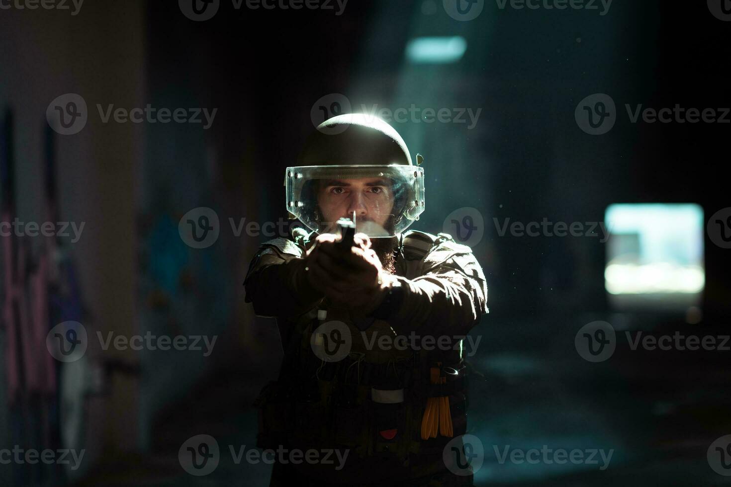 Soldier of army elite forces, special security service fighter with hidden behind mask and glasses face, in helmet and load carriage system, aiming with service pistol low key. photo