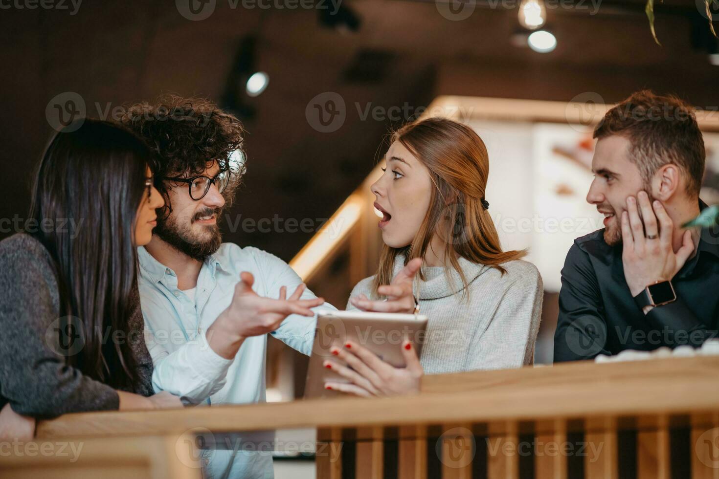 A group of young entrepreneurs on a coffee break discuss the project while using modern editing tablets, a smartphone and a laptop.Business concept photo