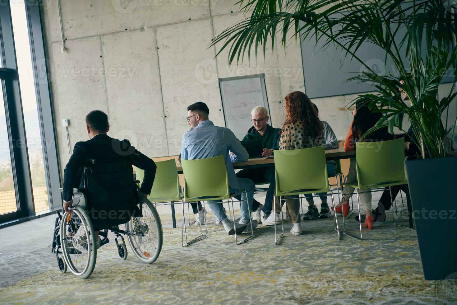 un diverso grupo de negocio profesionales, incluso un persona con un discapacidad, reunido a un moderno oficina para un productivo y inclusivo reunión. foto