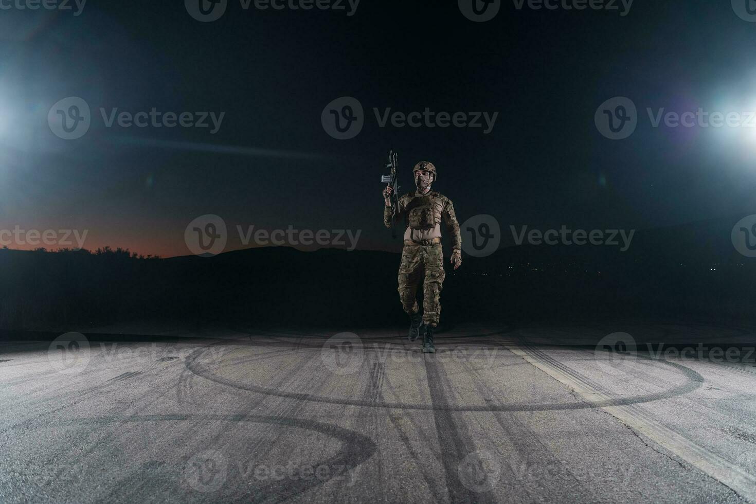 Army soldier in Combat Uniforms with an assault rifle, plate carrier and combat helmet going on a dangerous mission on a rainy night. photo