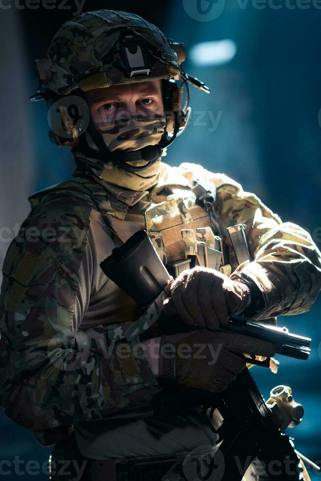 Soldier of army elite forces, special security service fighter with hidden behind mask and glasses face, in helmet and load carriage system, aiming with service pistol low key. photo