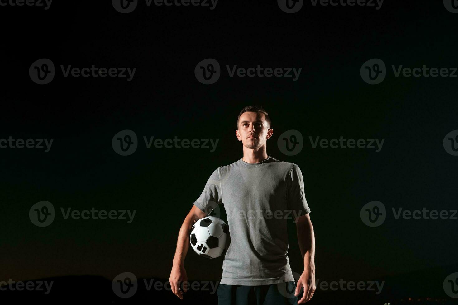 portrait of a young handsome soccer player man on a street playing with a football ball. photo