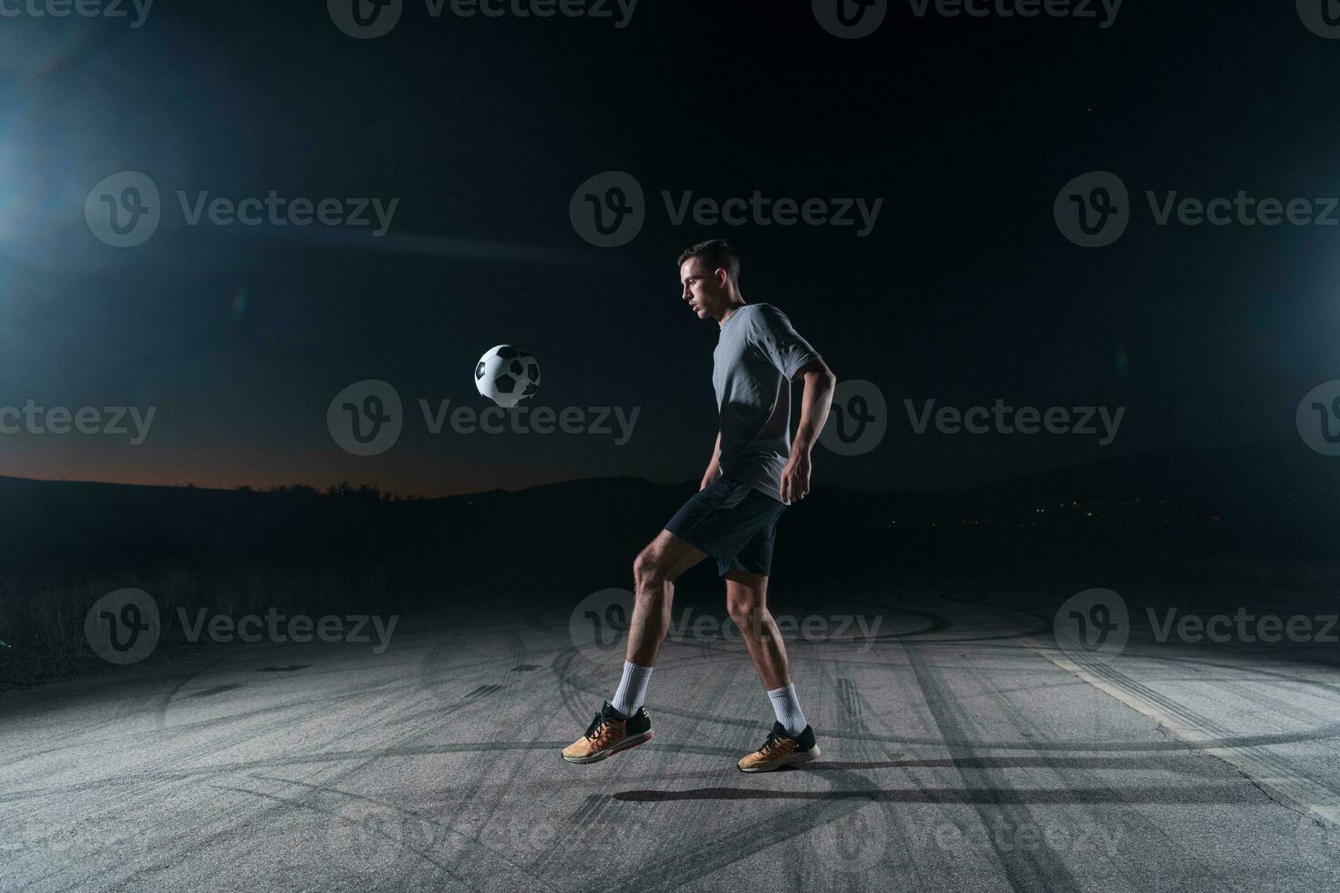 portrait of a young handsome soccer player man on a street playing with a football ball. photo