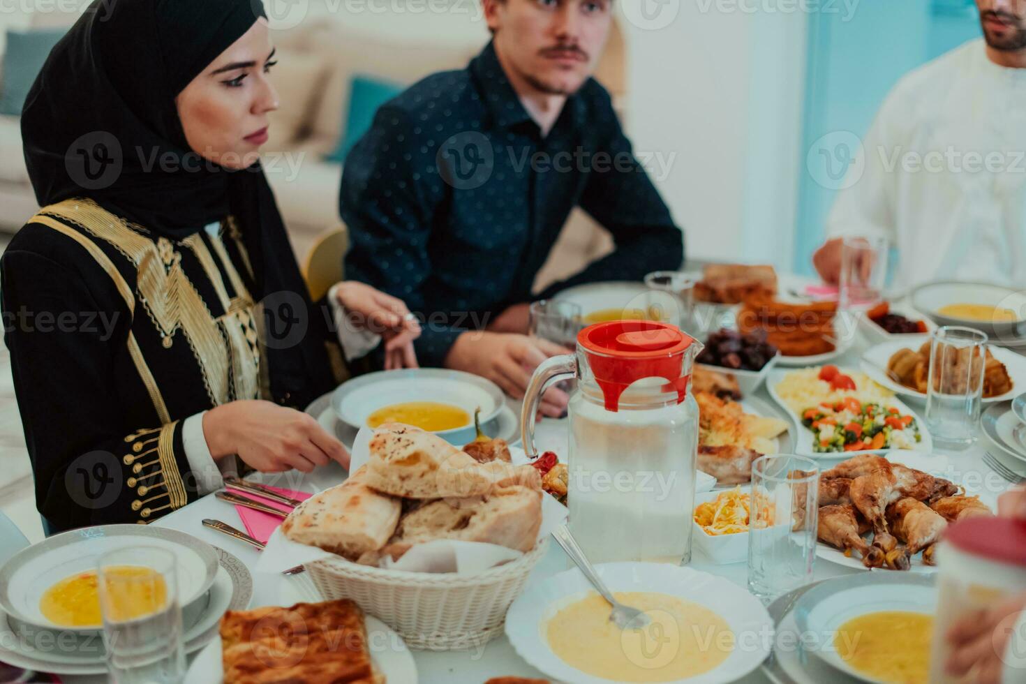 Muslim family having Iftar dinner drinking water to break feast. Eating traditional food during Ramadan feasting month at home. The Islamic Halal Eating and Drinking in modern home photo