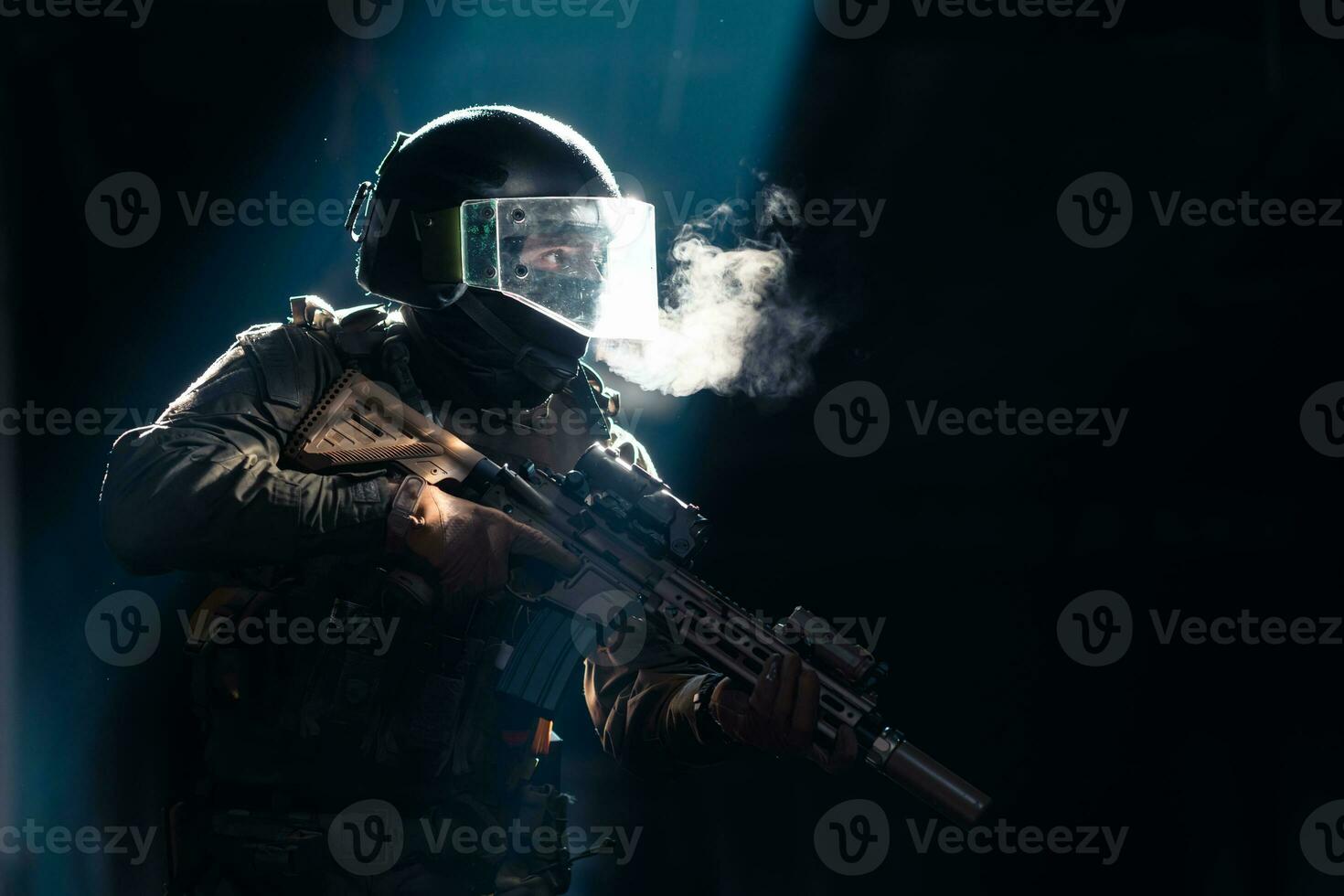 Army soldier in Combat Uniforms with an assault rifle and combat helmet night mission dark background. Blue and purple gel light effect. photo