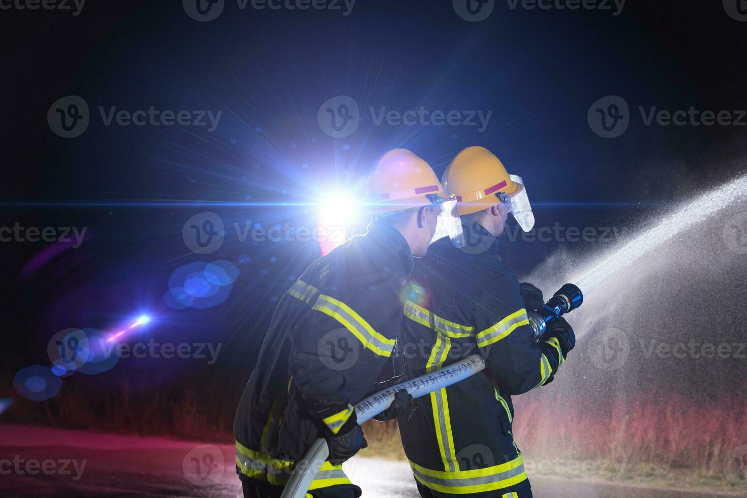 Firefighters use a water hose to eliminate a fire hazard. Team of firemen in the dangerous rescue mission. photo