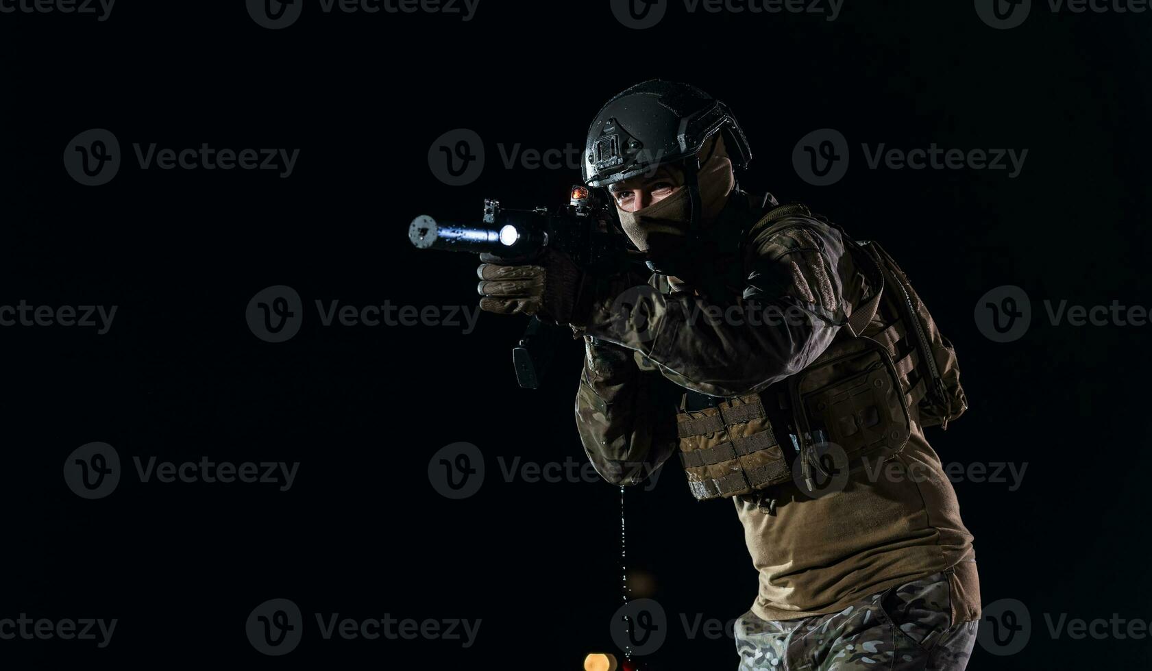 Ejército soldado en combate uniformes con un asalto rifle, plato portador y combate casco yendo en un peligroso misión en un lluvioso noche. foto