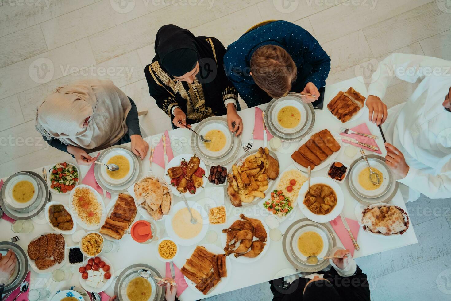 parte superior ver de musulmán familia teniendo iftar cena Bebiendo agua a descanso banquete. comiendo tradicional comida durante Ramadán banquete mes a hogar. el islámico halal comiendo y Bebiendo en moderno hogar foto