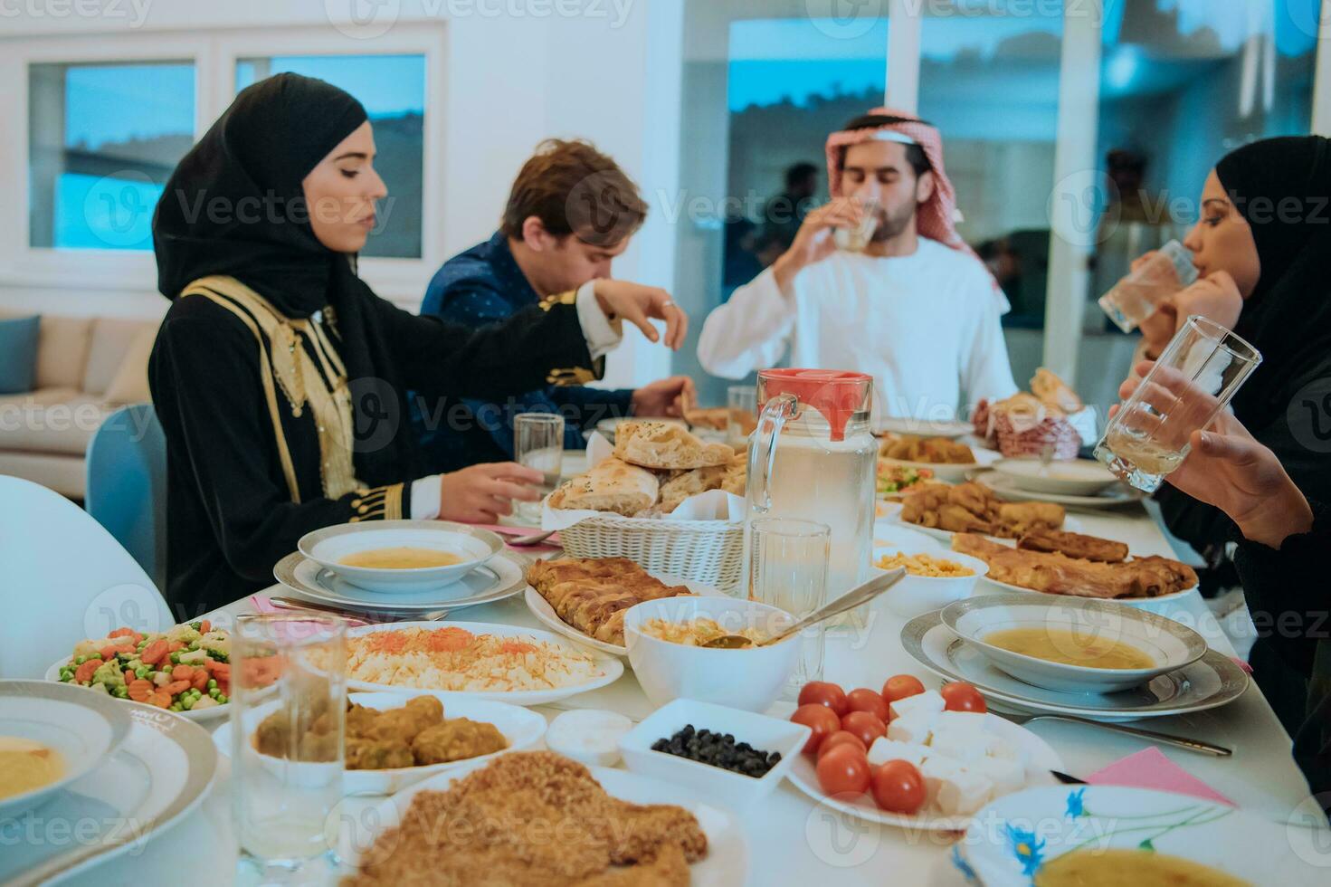 Muslim family having Iftar dinner drinking water to break feast. Eating traditional food during Ramadan feasting month at home. The Islamic Halal Eating and Drinking in modern home photo