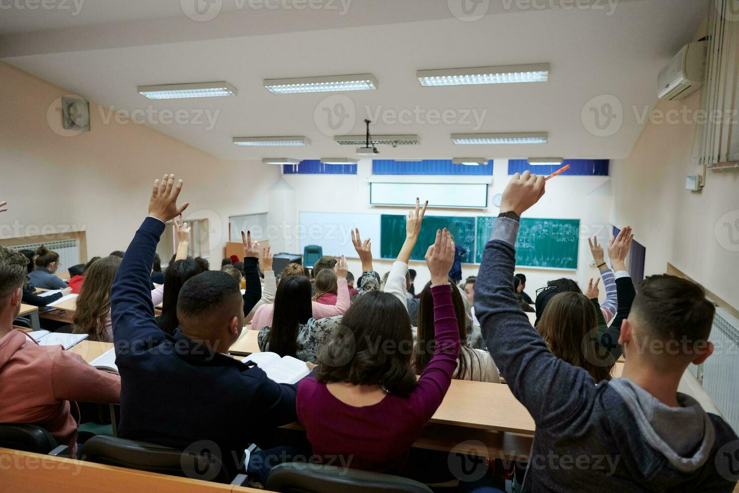 manos y brazos levantados de un gran grupo de personas en la sala de clase foto