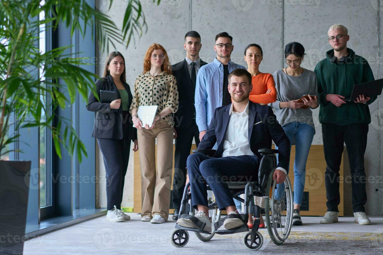 diverso grupo de negocio gente, incluso un empresario en un silla de ruedas en un moderno oficina foto