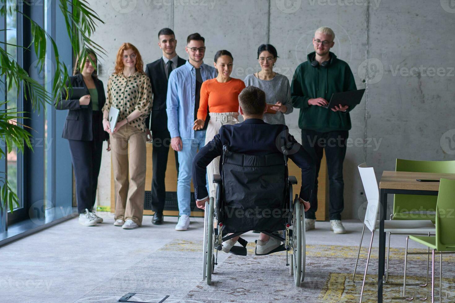 A group of diverse entrepreneurs gather in a modern office to discuss business ideas and strategies, while a colleague in a wheelchair joins them. photo