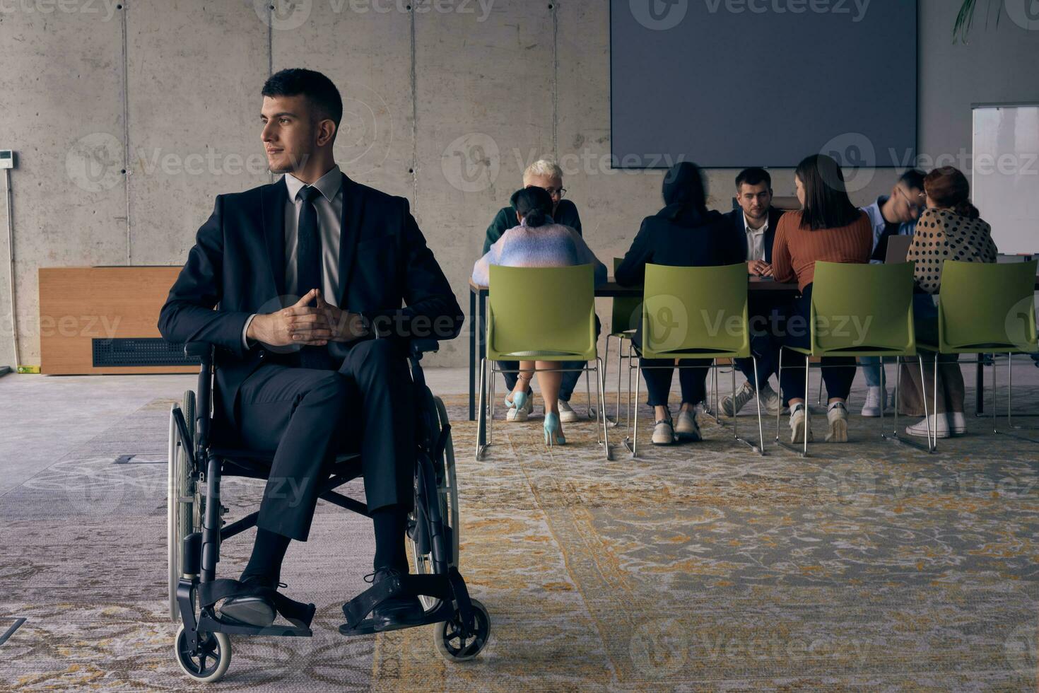 Businessman in a wheelchair commands attention, symbolizing resilience and success amidst a dynamic modern office environment. photo