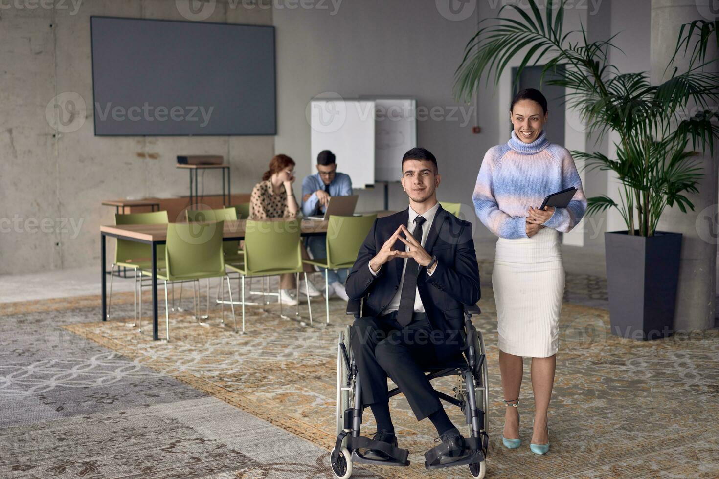 A businessman in a wheelchair and his female colleague together in a modern office, representing the power of teamwork, inclusion and support, fostering a dynamic and inclusive work environment. photo