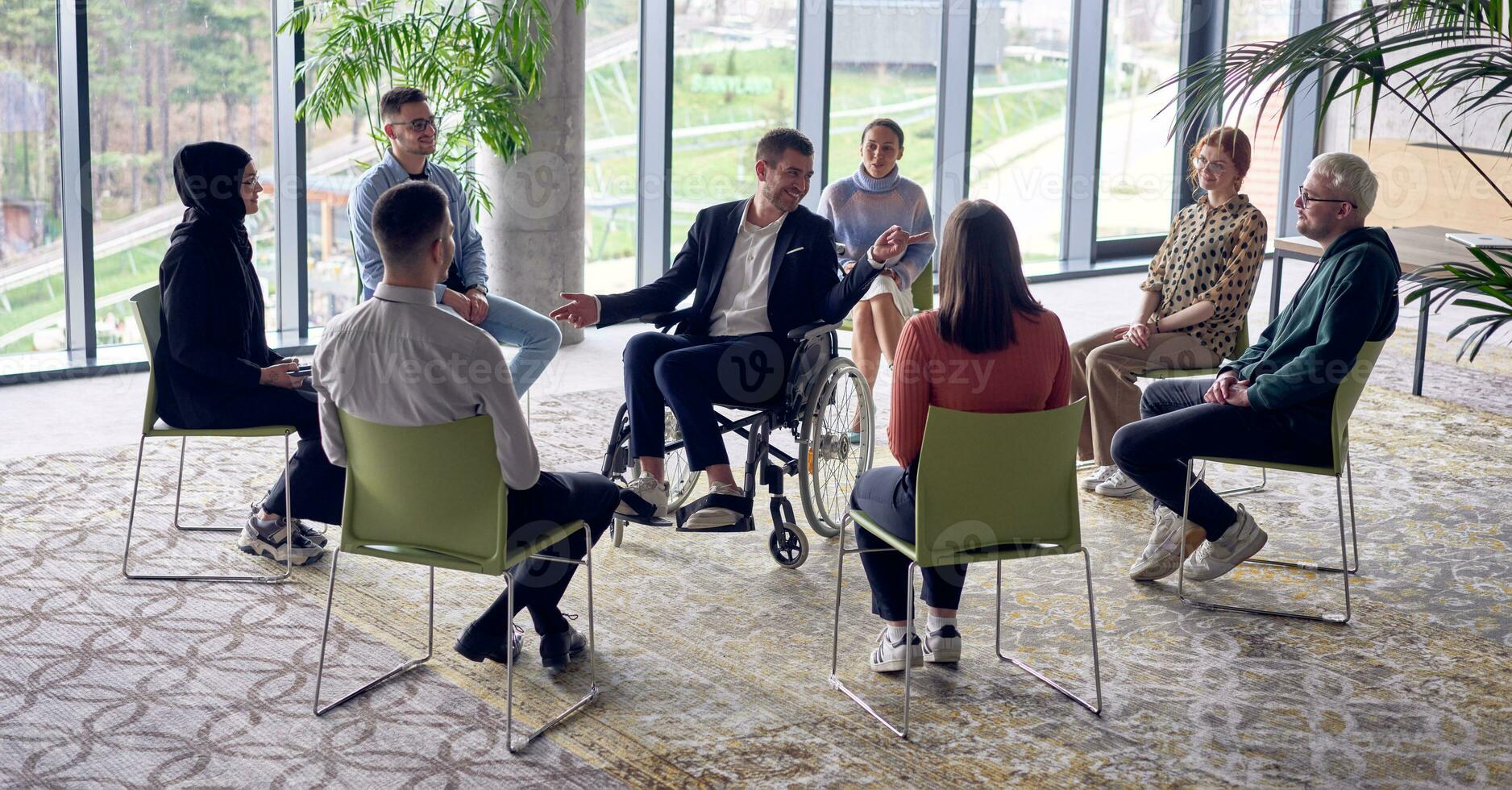 A businessman in a wheelchair in the center of the circle, passionately sharing his business ideas with his colleagues, fostering an atmosphere of collaboration and innovation in a dynamic and engaging workplace. photo