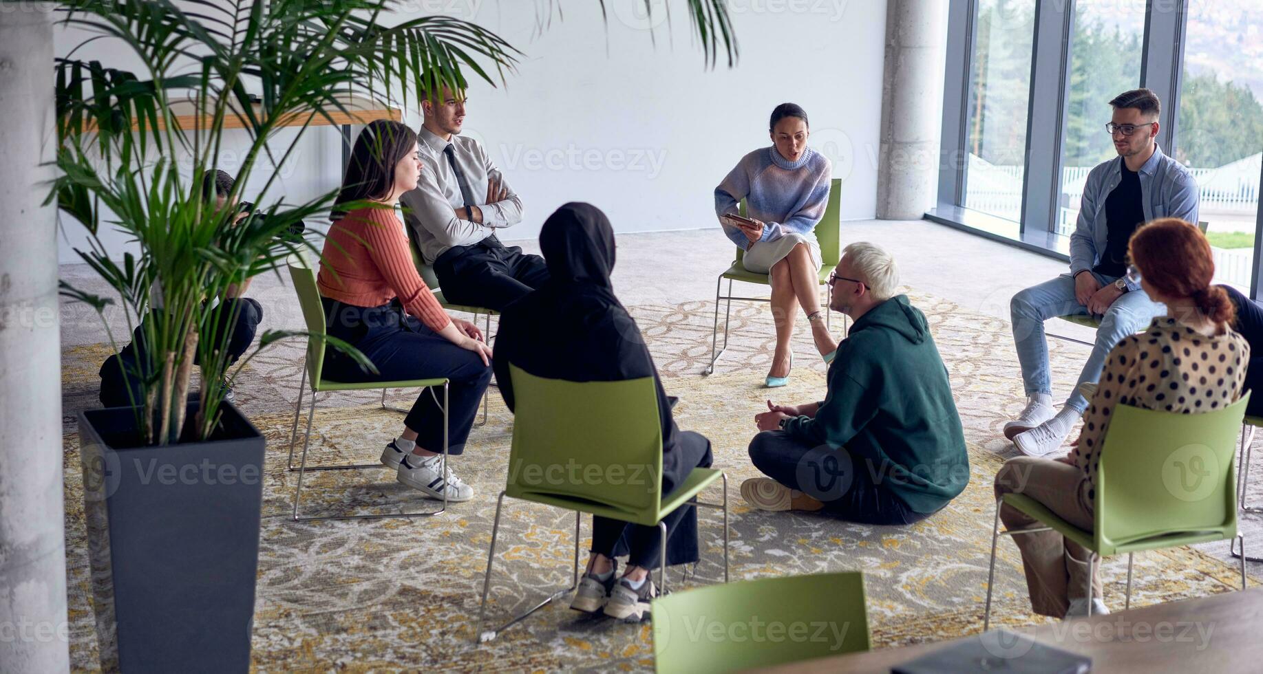 un hombre sentado a el centrar de un círculo, apasionadamente compartiendo su negocio ideas con su colegas, Fomentando un atmósfera de colaboración y innovación en un dinámica y atractivo lugar de trabajo. foto