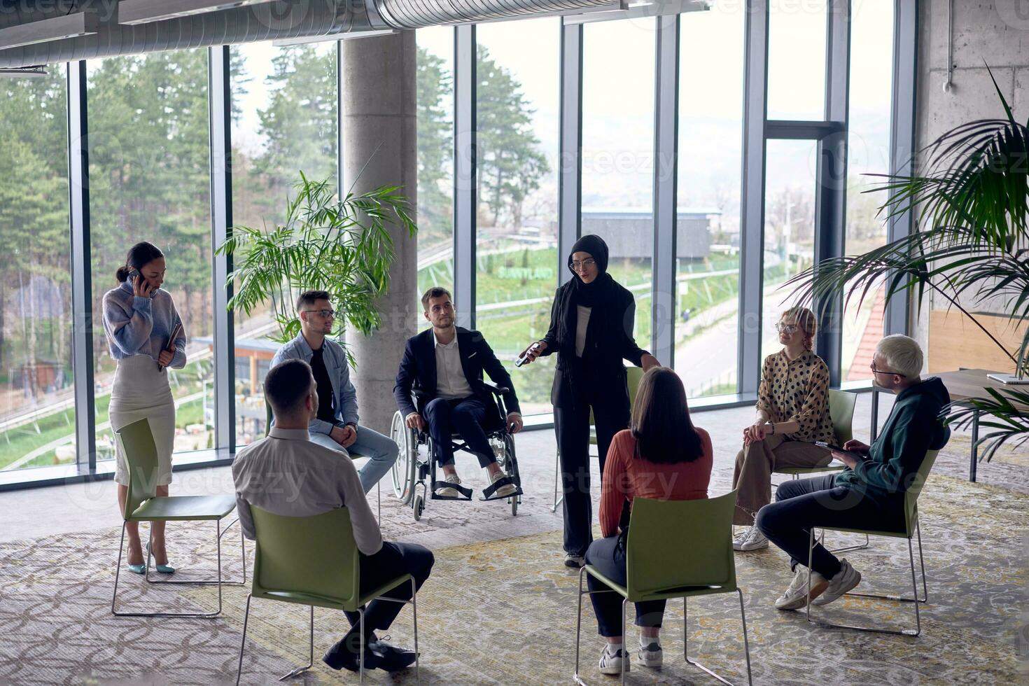A business hijab woman in the center of a circle, passionately sharing his business ideas with his colleagues, fostering an atmosphere of collaboration and innovation in a dynamic and engaging workplace. photo