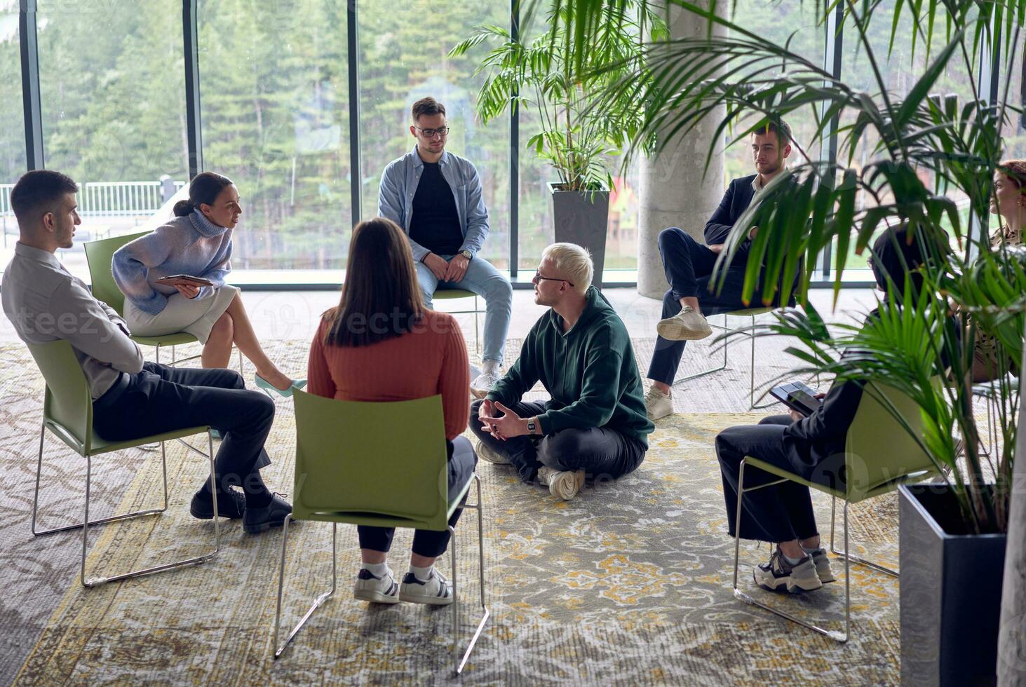 un hombre sentado a el centrar de un círculo, apasionadamente compartiendo su negocio ideas con su colegas, Fomentando un atmósfera de colaboración y innovación en un dinámica y atractivo lugar de trabajo. foto