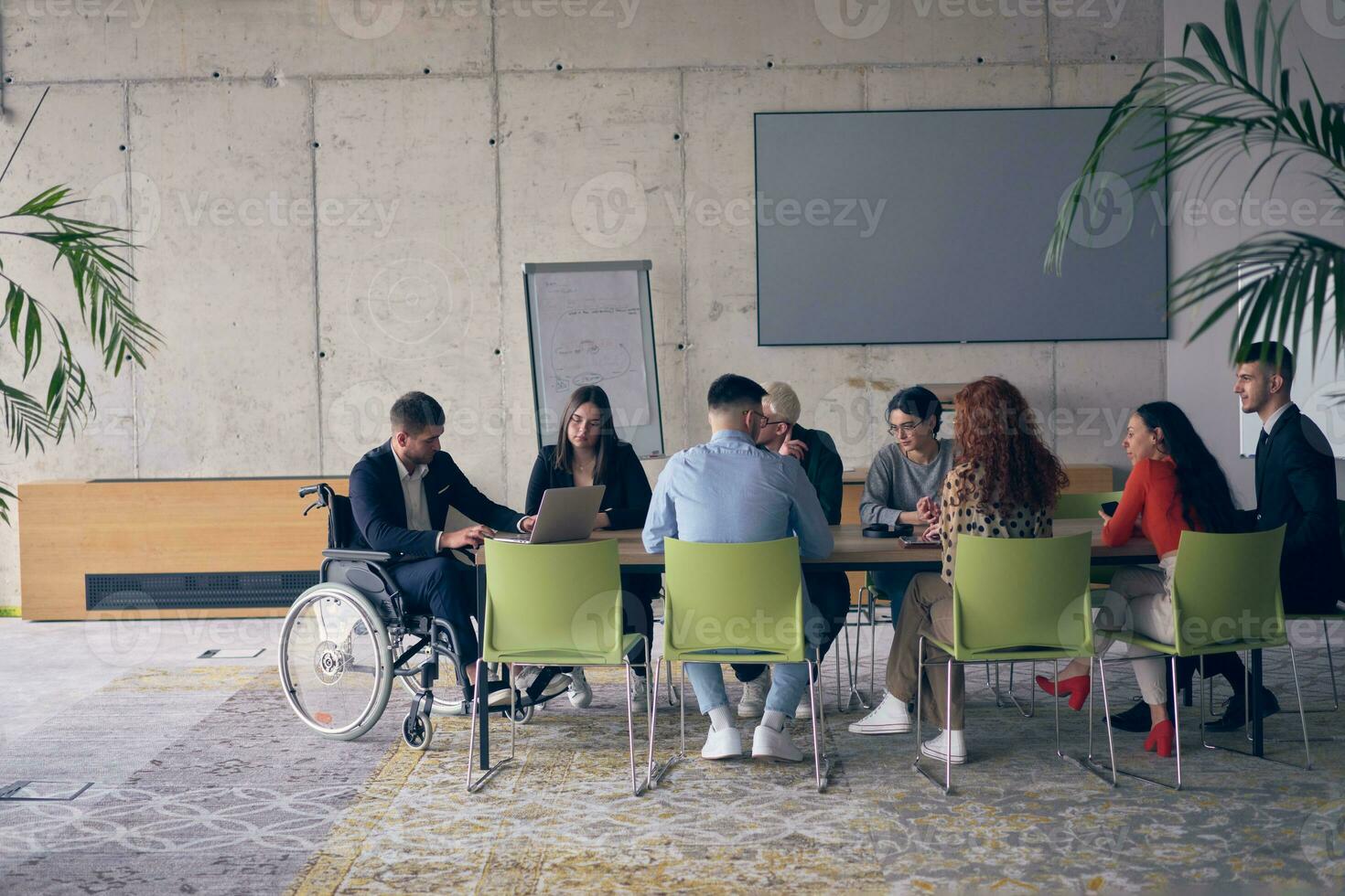 un diverso grupo de negocio profesionales, incluso un persona con un discapacidad, reunido a un moderno oficina para un productivo y inclusivo reunión. foto