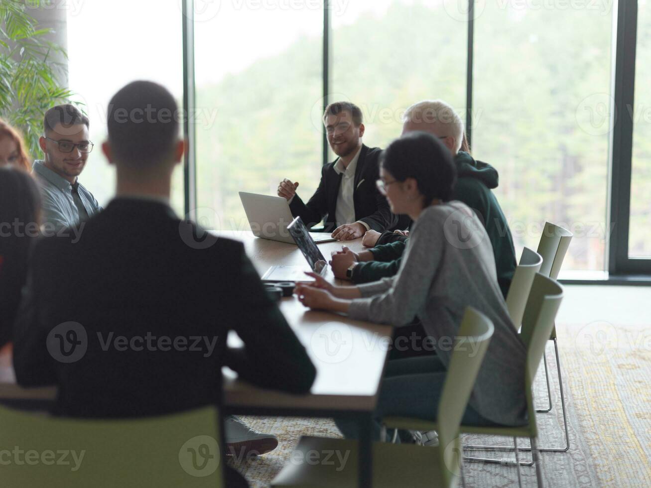 A diverse group of business professionals, including an person with a disability, gathered at a modern office for a productive and inclusive meeting. photo
