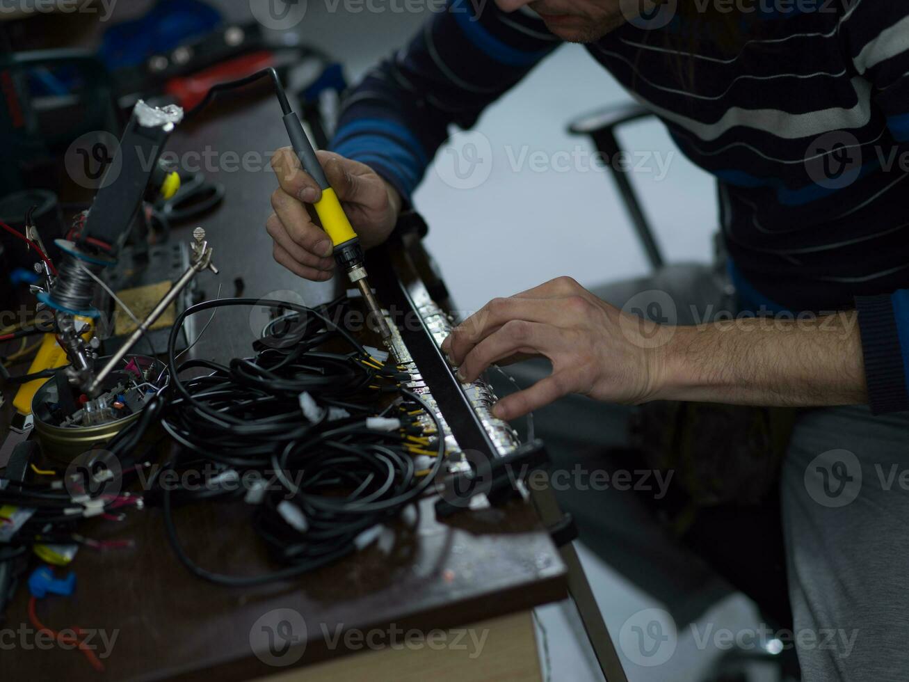 Industrial worker man soldering cables of manufacturing equipment in a factory. Selective focus photo