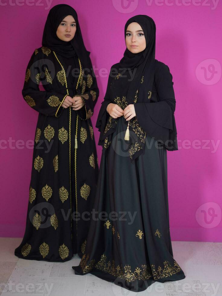 dos hermosa musulmán mujer en de moda vestir con hijab aislado en moderno rosado antecedentes representando concepto de moderno islam y Ramadán kareem foto
