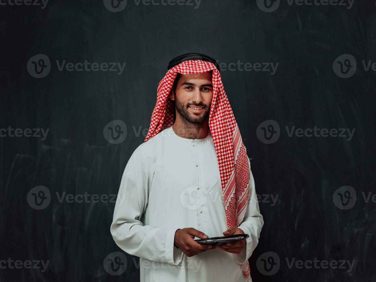 joven árabe musulmán empresario utilizando tableta computadora vistiendo hijab ropa en frente de negro pizarra foto