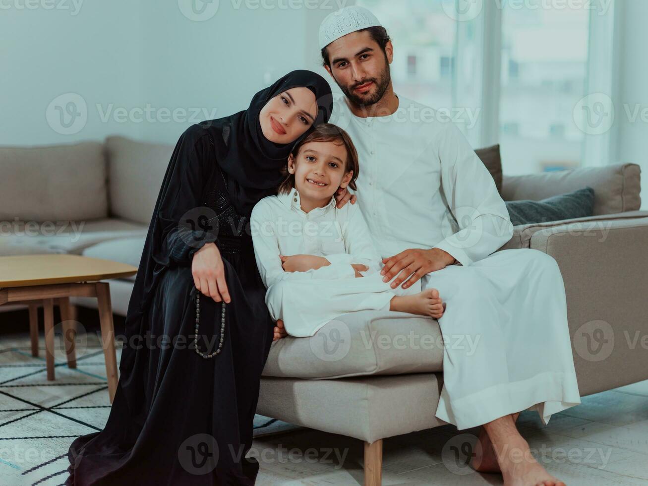 Happy Muslim family enjoying the holy month of Ramadan while praying and reading the Quran together in a modern home photo