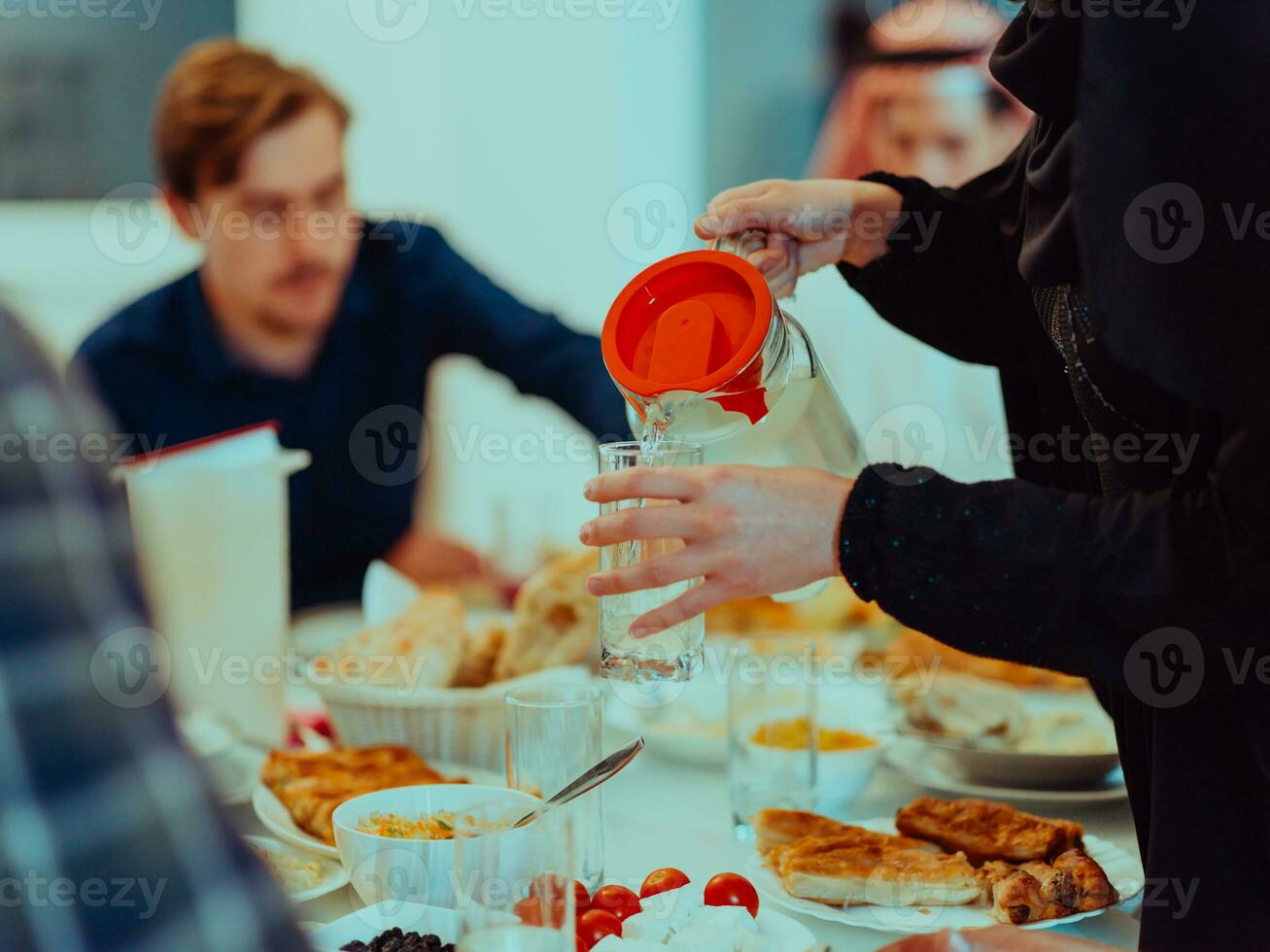 Eid Mubarak Muslim family having Iftar dinner drinking water to break feast. Eating traditional food during Ramadan feasting month at home. The Islamic Halal Eating and Drinking photo