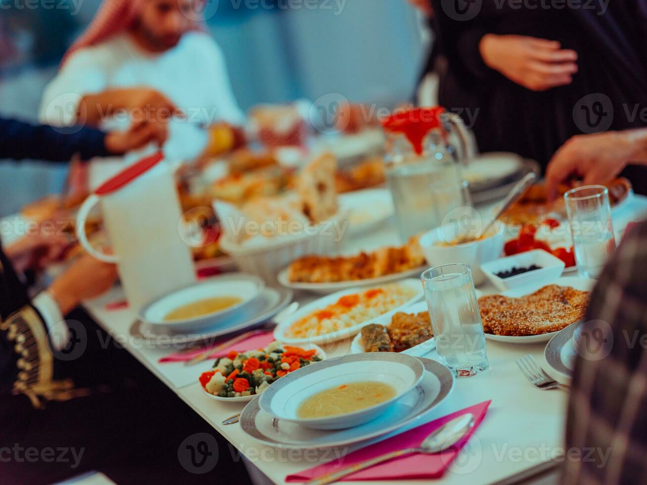 eid Mubarak musulmán familia teniendo iftar cena Bebiendo agua a descanso banquete. comiendo tradicional comida durante Ramadán banquete mes a hogar. el islámico halal comiendo y Bebiendo foto