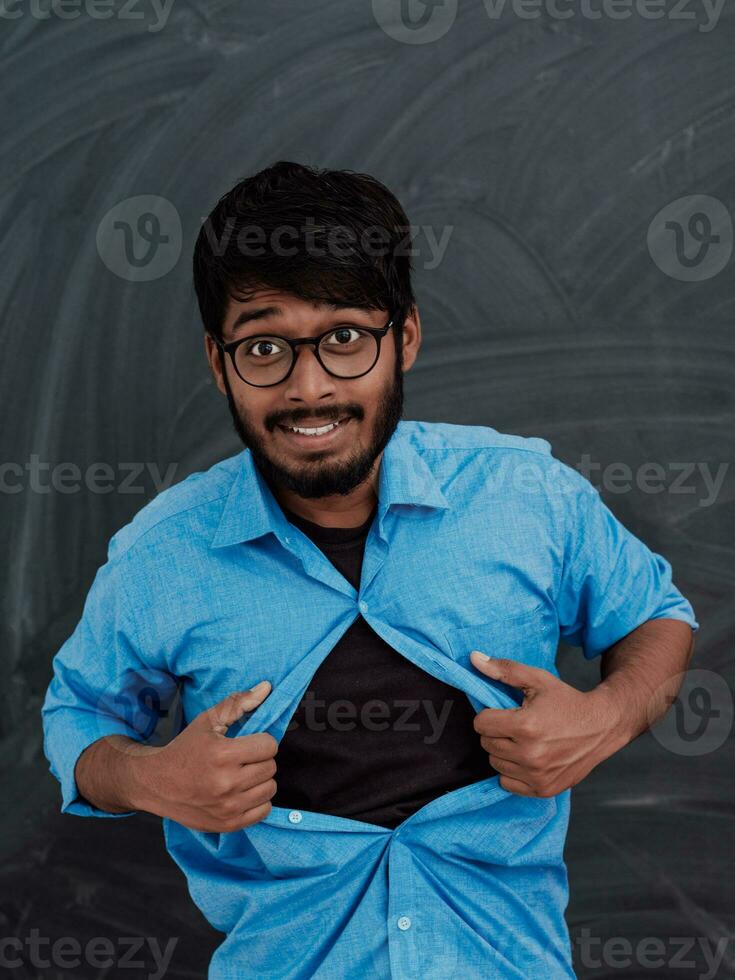 A symbolic photo of an Indian boy showing the superman sign in front of the school blackboard