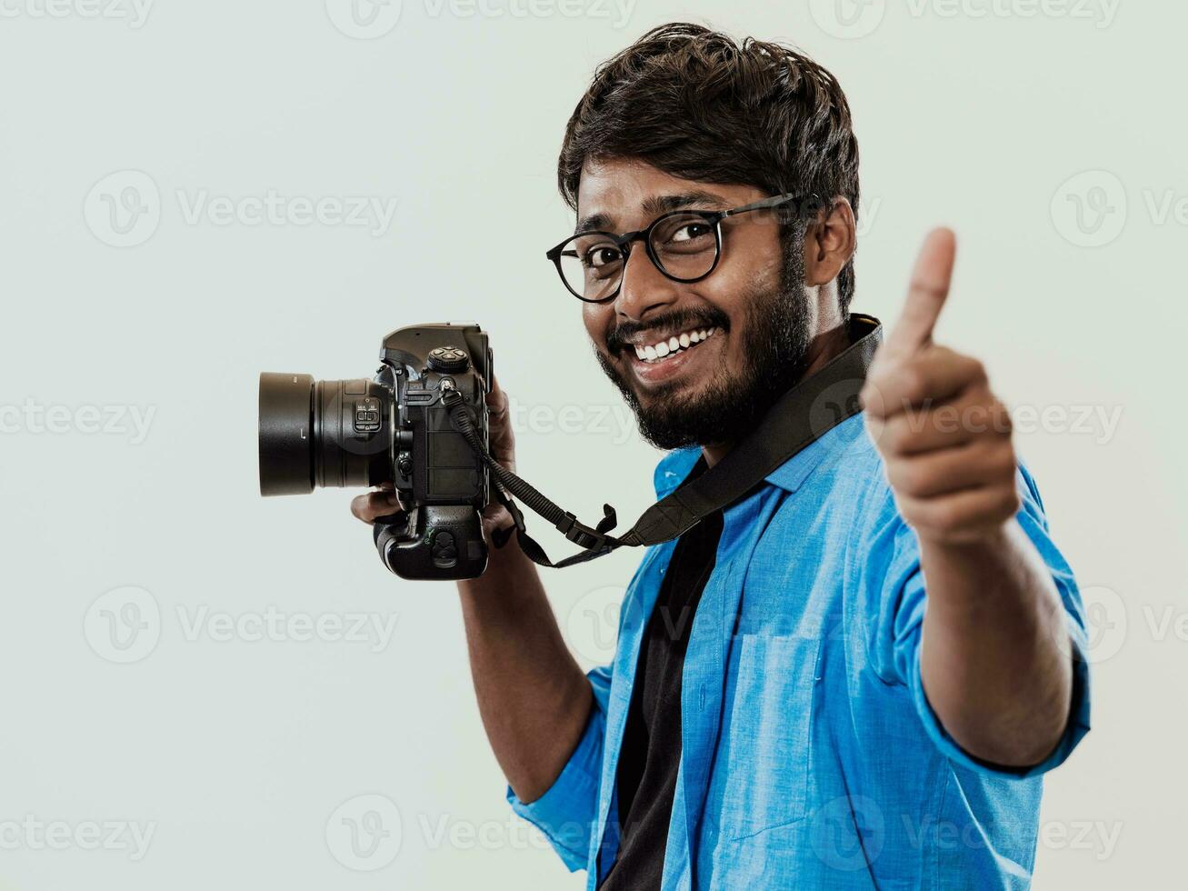 profesional fotógrafo teniendo dslr cámara tomando imagen.indio hombre fotografía entusiasta tomando foto mientras en pie en azul antecedentes. estudio Disparo