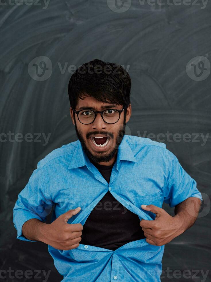 A symbolic photo of an Indian boy showing the superman sign in front of the school blackboard