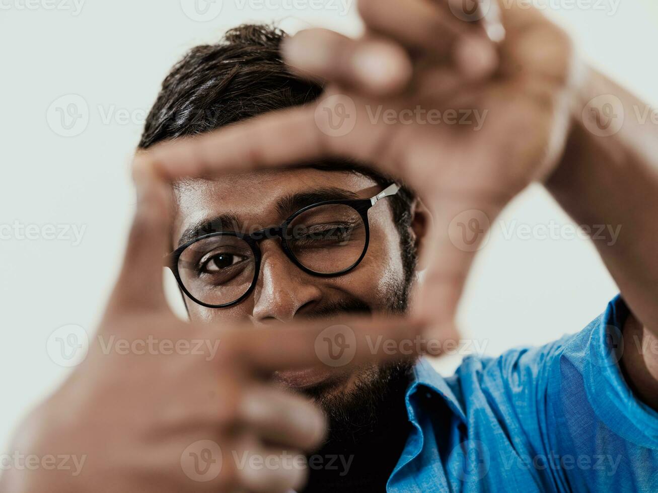 Young handsome man focusing with fingers, framing with hands isolated on grey background. Close up portrait photo