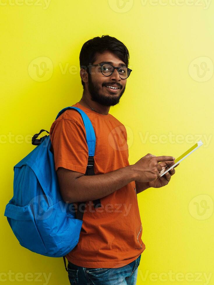 Indian student with blue backpack, glasses and notebook posing on gray and green background. The concept of education and schooling. Time to go back to school photo