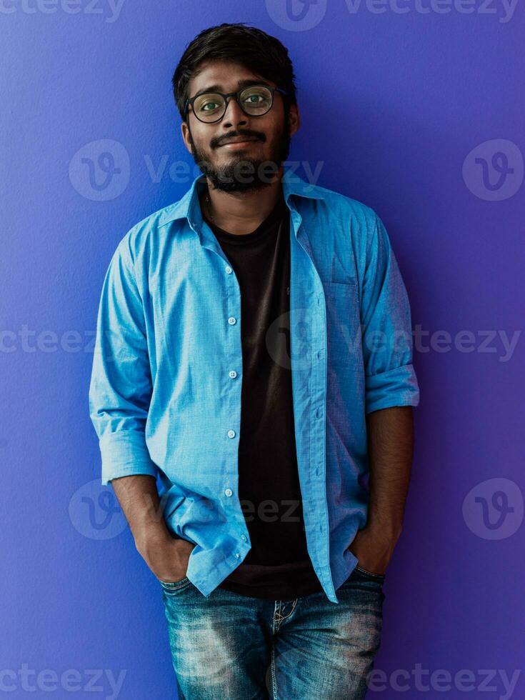 Indian student with blue backpack, glasses and notebook posing on green background. The concept of education and schooling. Time to go back to school photo