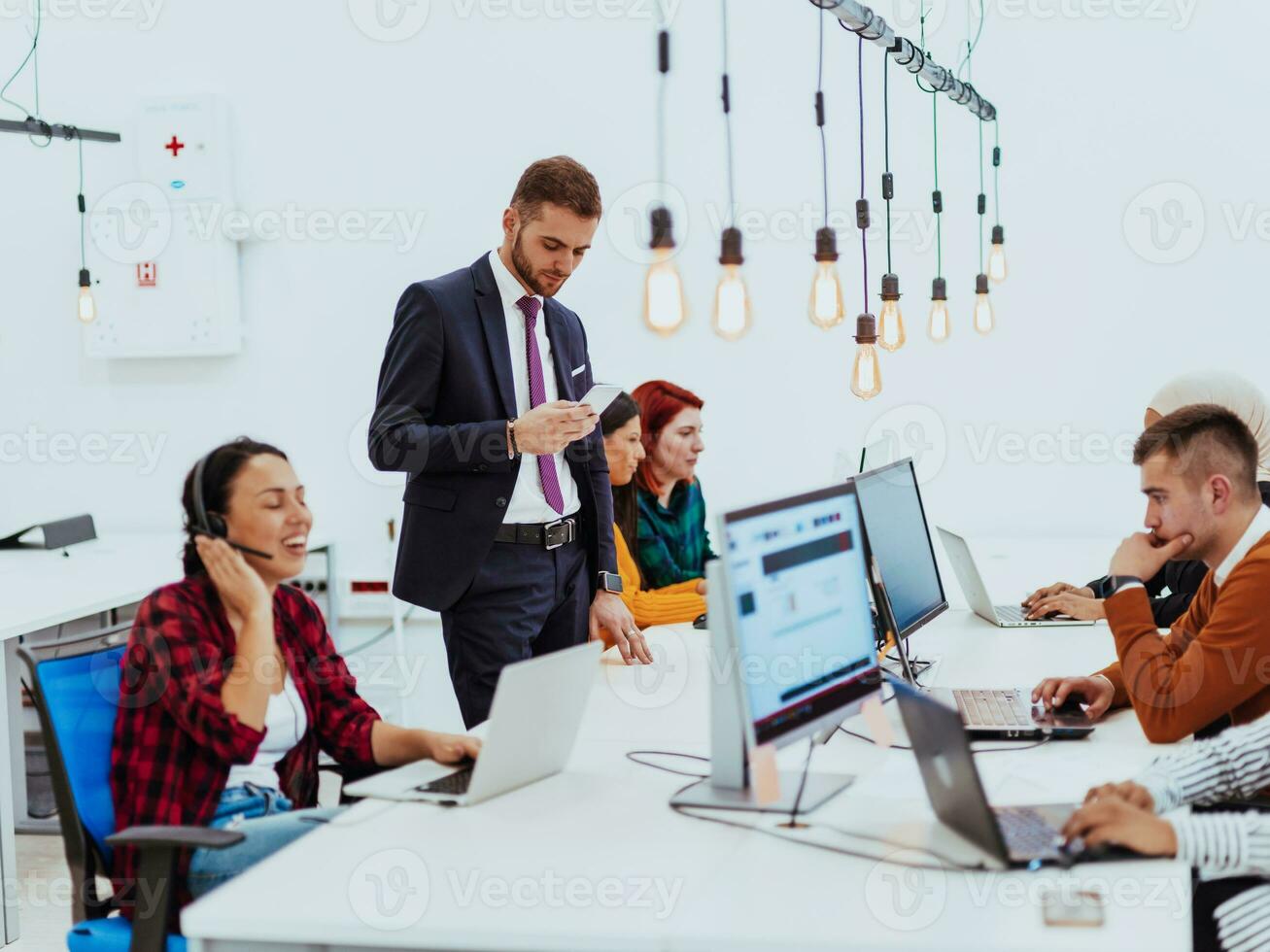 Group of multi-ethnic colleagues working on desktop computers, laptop and sharing their ideas in a modern office space.Young influencers work on online marketing projects. photo
