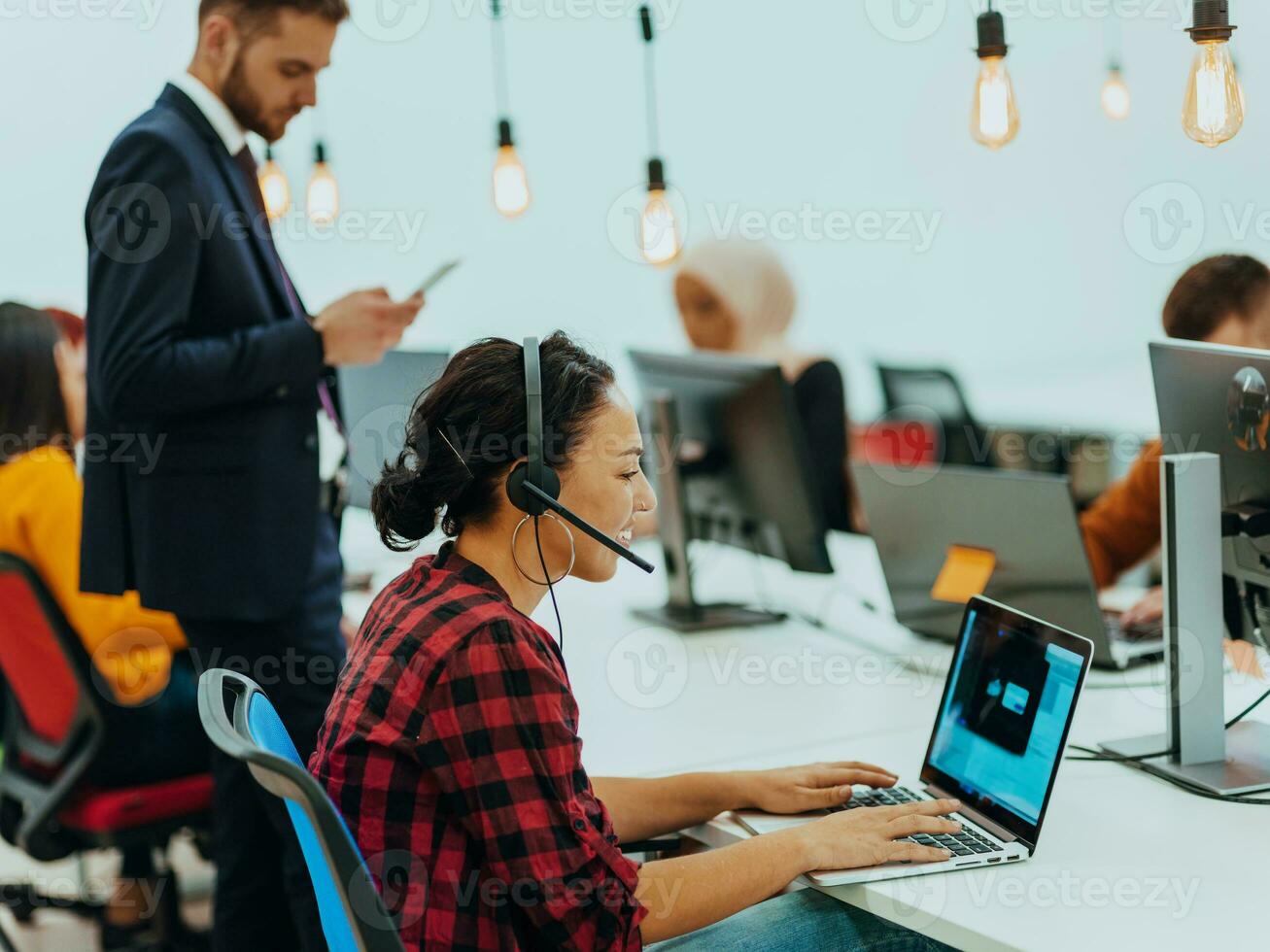 Group of multi-ethnic colleagues working on desktop computers, laptop and sharing their ideas in a modern office space.Young influencers work on online marketing projects. photo