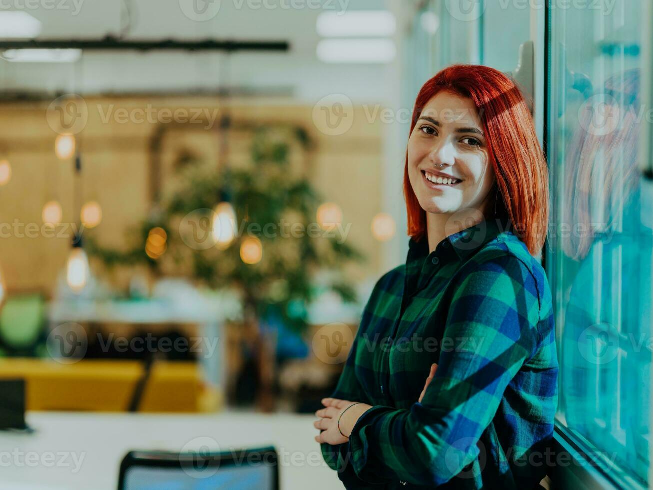 Headshot portrait of a modern woman with crossed arms in the office at night by the window photo