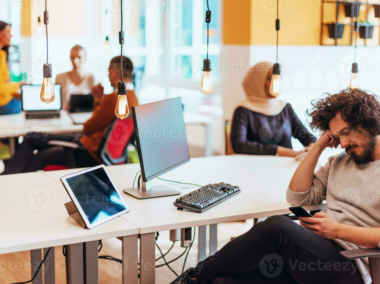 Group of multi-ethnic colleagues working on desktop computers, laptop and sharing their ideas in a modern office space.Young influencers work on online marketing projects. photo
