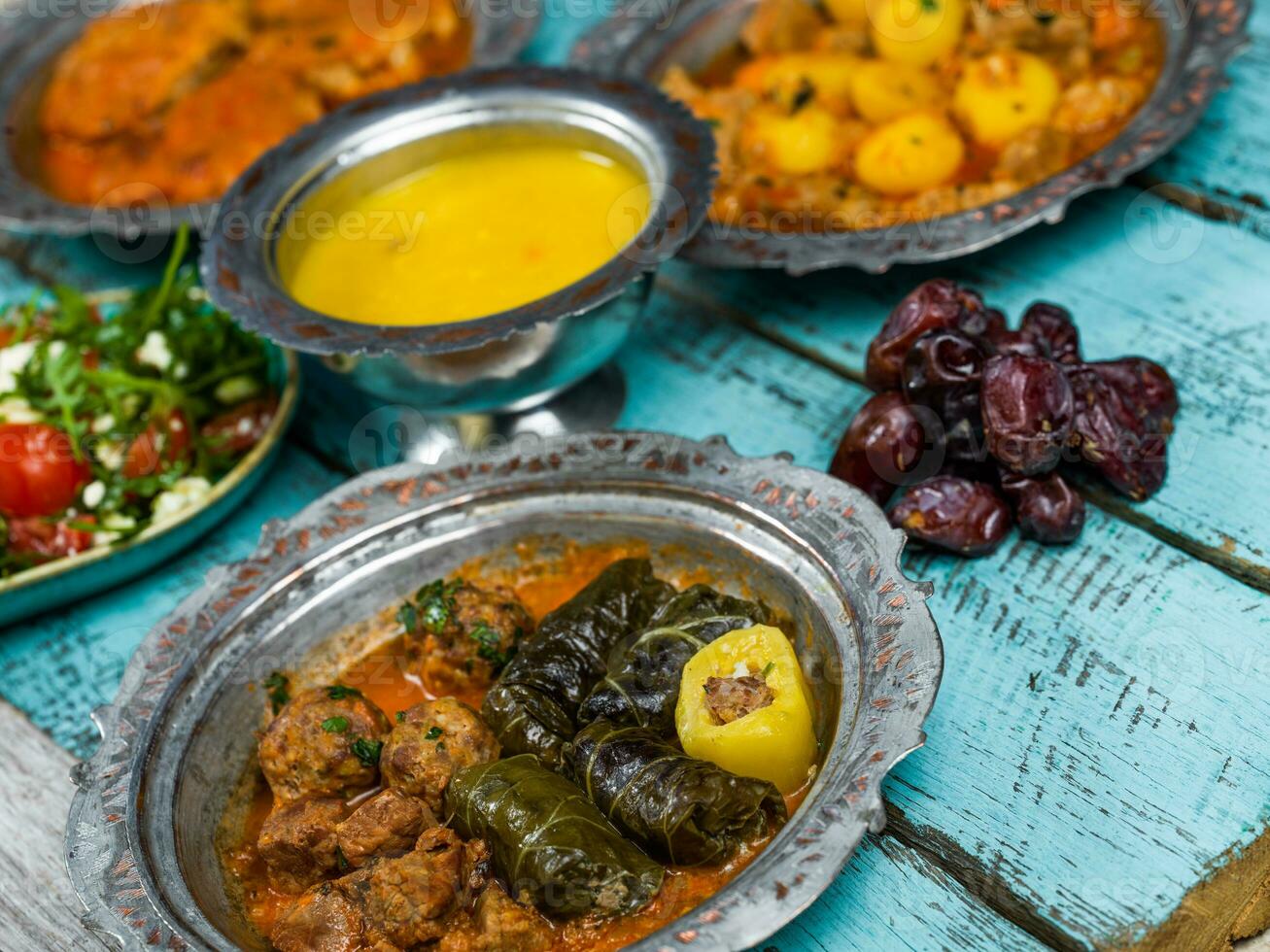 Eid Mubarak Traditional Ramadan Iftar dinner. Assorted tasty food in authentic rustic dishes on wooden blue background. Turkish Bosnian food meat kebab, pita, Sarma, klepe, sogan dolma. photo