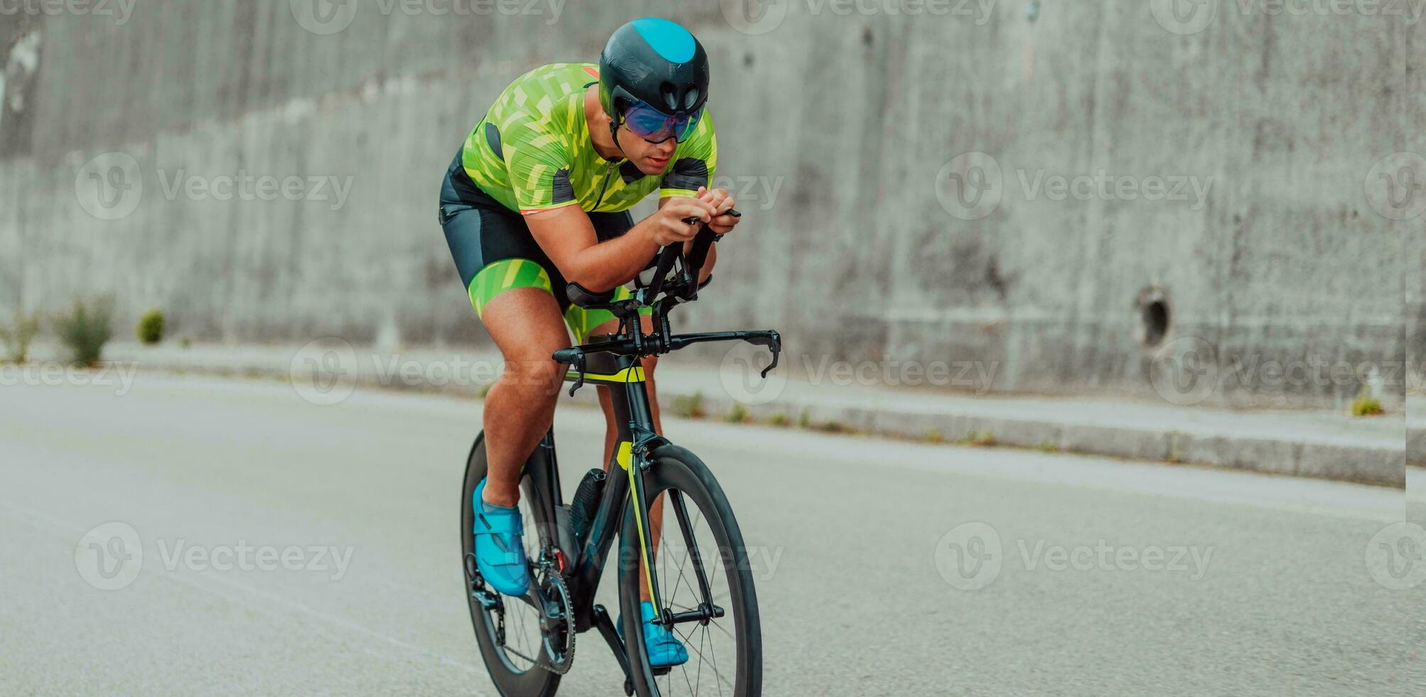 Full length portrait of an active triathlete in sportswear and with a protective helmet riding a bicycle. Selective focus photo