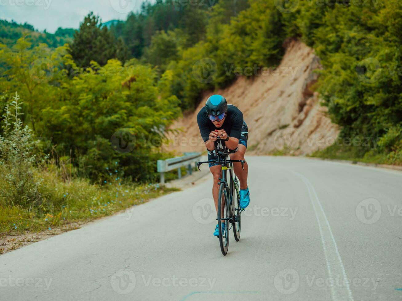 lleno longitud retrato de un activo triatleta en ropa de deporte y con un protector casco montando un bicicleta. selectivo atención foto