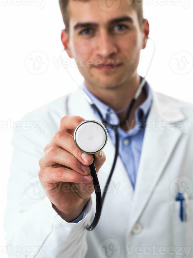 Portrait of hero in a white coat. Cheerful smiling young doctor with a stethoscope in a medical hospital standing against a white background. Coronavirus covid-19 danger alert photo