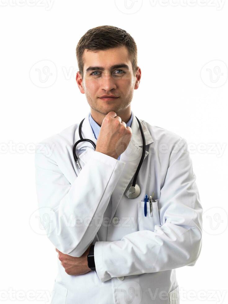 Portrait of hero in white coat. Cheerful smiling young doctor with stethoscope in medical hospital standing against white background. Coronavirus covid-19 danger alert photo