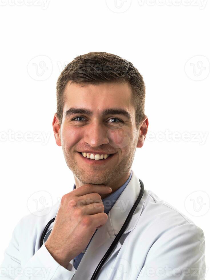 Portrait of hero in white coat. Cheerful smiling young doctor with stethoscope in medical hospital standing against white background. Coronavirus covid-19 danger alert photo