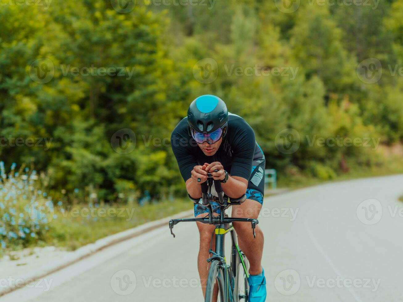 Full length portrait of an active triathlete in sportswear and with a protective helmet riding a bicycle. Selective focus photo