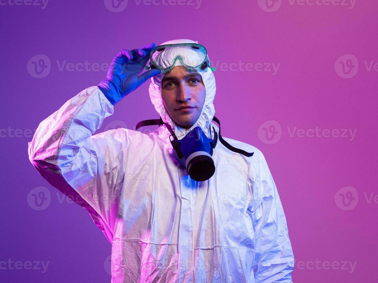 Coronavirus covid-19 pandemic. Doctor scientist wearing protective biological suit and mask due to global healthcare epidemic warning and danger background in blue and pink neon lights background. photo