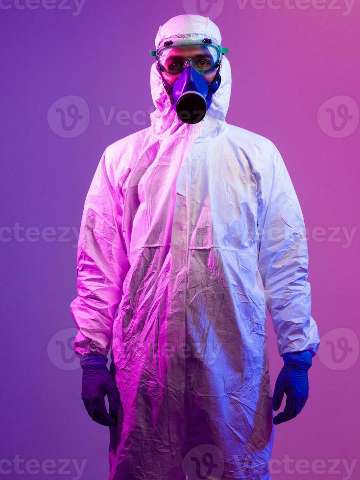 Coronavirus covid-19 pandemic. Doctor scientist wearing protective biological suit and mask due to global healthcare epidemic warning and danger background in blue and pink neon lights background. photo